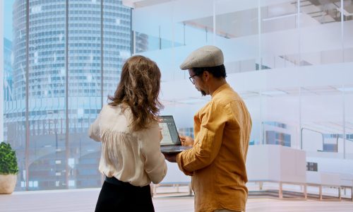 Professionals and realtor planning an urban office space renovation for relocation, negotiating a property investment. Examining blueprints and considering a leasing contract deal. Camera A.